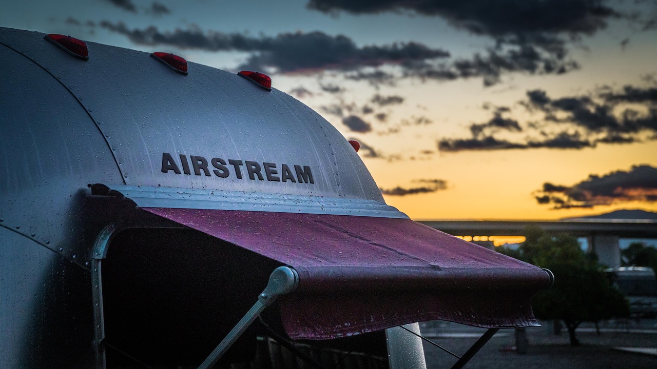 Airstream trailer with awning at sunset on an RV site