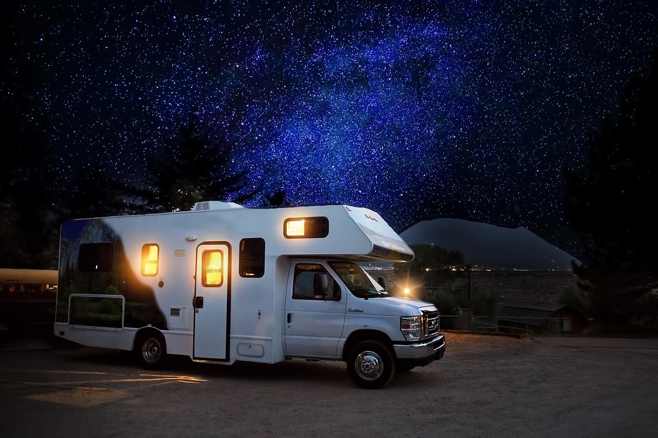 RV lit up under a starry night sky at a campground